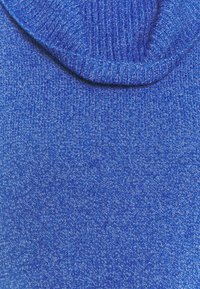 Gros plan sur un tissu tricoté bleu avec un col côtelé plié, montrant clairement la texture et les motifs de points.