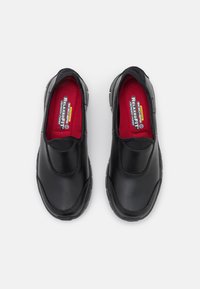 Černé nazouvací boty s hladkým koženým svrškem, červenou polstrovanou stélkou a texturovanou gumovou podrážkou. Obsahují elastické boční panely pro snadné obouvání.