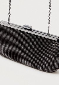 Fekete kézitáska textúrált felülettel, amelyet fényes gyöngyök borítanak, ezüst színű fémszerkezettel és lánc vállpánttal. Kompakt kialakítás.