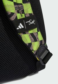 Svart nätrem med ett rutmönster i klar grön och grå, med en Adidas-logotyp och Jeremy Scott-märke.