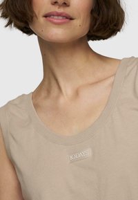 Top senza maniche beige con scollatura arrotondata, realizzato in morbido cotone. Presenta un'etichetta ricamata "10 DAYS" sulla parte anteriore, design minimalista.