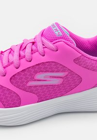 Zapatilla deportiva rosa con parte superior de malla, paneles rosa texturizados, cordones redondos y suela blanca que presenta un detalle sutil del logo.