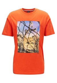 Pomarańczowa bawełniana koszulka z grafiką przedstawiającą pustynny krajobraz z wzorem ogrodzenia, okrągłym dekoltem, krótkimi rękawami i luźnym krojem.