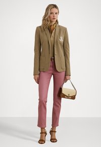 Beige räätälöity bleiseri kahdella taskulla, vaaleanpunaiset istuvat housut ja vanilja- sekä ruskeareunainen crossbody-laukku. Ruskeat remmihyvät, kuvioitu huiviyksityiskohta.