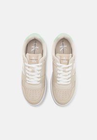 Sneaker beige con lacci bianchi, tomaia in pelle liscia, punta perforata, dettagli verde menta sul tallone e logo sulla linguetta.