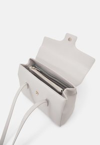 Grå läder toteväska med ett överhäng, guldklickspärr och två handtag. Inuti finns en ficka med dragkedja och ytterligare fack.