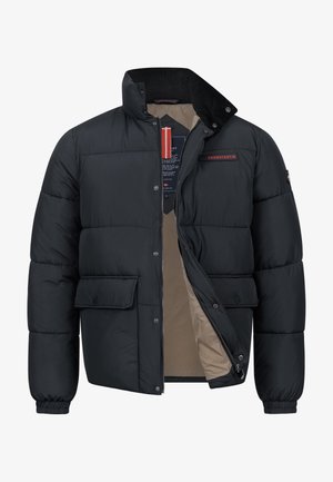 Svart polstret jakke med høy krage, lommer med klaff foran, delvis åpnet glidelås som viser beige innerfôr, og merket røde og svarte etiketter.