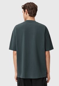 Ciemnozielony t-shirt bawełniany z krótkim rękawem, okrągłym dekoltem i luźnym krojem. Gładka tekstura bez widocznych wzorów lub akcentów.