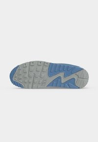 Σόλα παπουτσιού Nike με γκρί και μπλε λάστιχο που έχει τετράγωνα και κυματιστά σχέδια και το λογότυπο Nike κοντά στο κέντρο.