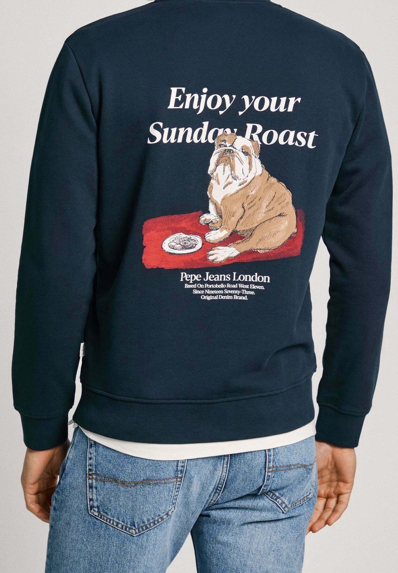 Sudadera navy con una ilustración de un bulldog y el texto "Disfruta de tu asado de domingo" en la espalda; tejido suave, puños y cintura acanalados.