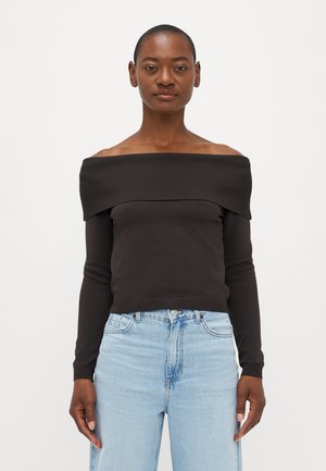 Black off-the-shoulder top with ribbed neckline, long sleeves, smooth texture, paired with light blue high-waisted denim jeans.