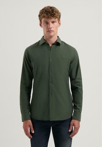 Overhemd met knopen in donkergroene stof, lange mouwen, kraag, geborduurd logo op de borst, slim fit, gladde textuur.