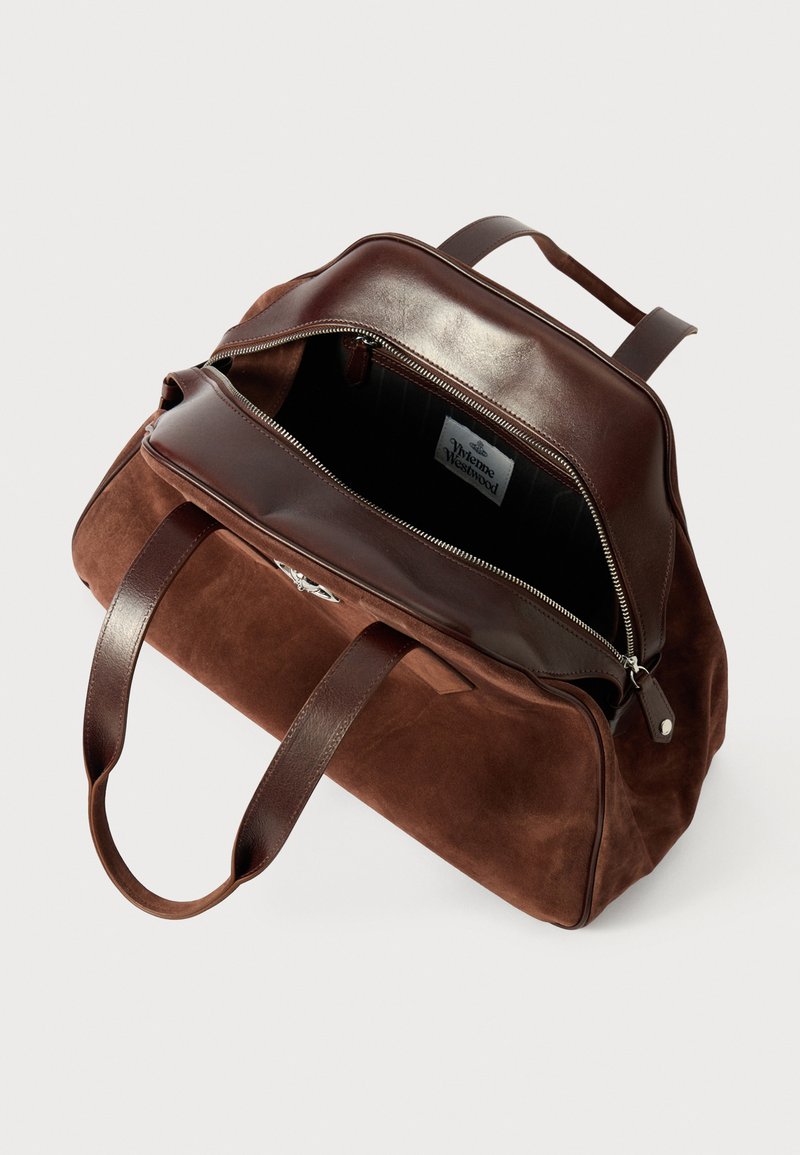 Duffel bag de ante marrón con detalles de cuero, cierre de cremallera y dos asas robustas. El interior presenta una etiqueta y un forro negro.