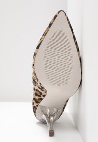 Chaussure à talon haut en imprimé léopard avec un bout pointu, talon en plastique transparent et semelle striée. La texture est douce avec une finition semblable à du fourrure.