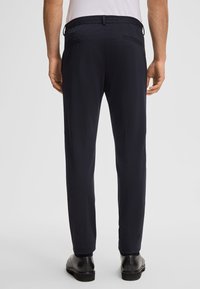 Pantaloni navy con elastico in vita, dotati di due tasche laterali e un design a gamba dritta, realizzati in un tessuto liscio e elastico.