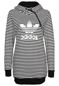 Pruhovaná černobílá mikina s kapucí a klokaní kapsou, se stahovacími šňůrkami na kapuci a výrazným reflexním logem adidas umístěným na přední straně.