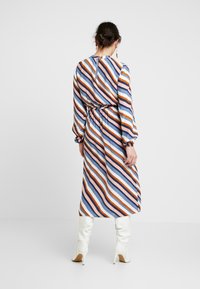 Langärmliges, knielanges Kleid mit mehrfarbigen diagonalen Streifen in Blau, Orange und Weiß. Elastischer Taillenbund, hoher Ausschnitt, Reißverschluss im Rücken.