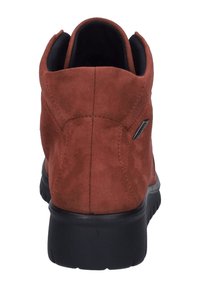 Brązowe zamszowe botki za kostkę z wyściełanym kołnierzem, czarną gumową podeszwą i subtelnymi detalami w stębnowaniu. Posiadają mały akcent z logo po boku.