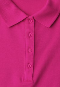 Chemise rose vif à col avec quatre boutons assortis sur la patte de boutonnage avant, tissu tricoté texturé visible.