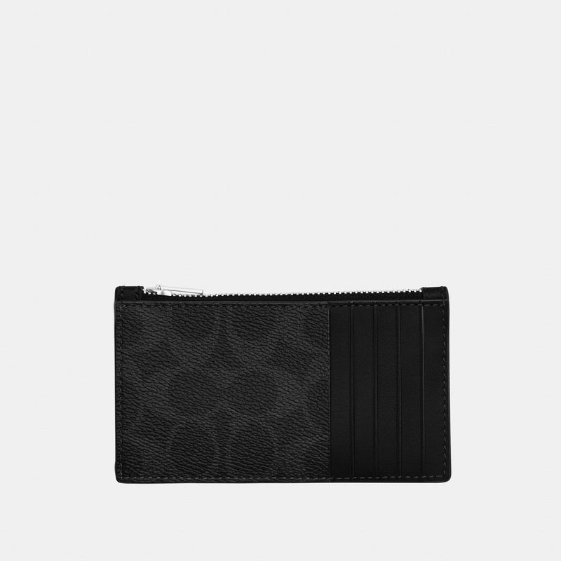 Portatarjetas de cuero negro con un compartimento con cremallera en la parte superior y cuatro ranuras verticales para tarjetas en el lado derecho sobre un fondo claro.
