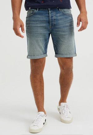 Jeansshorts in Hellblau mit einem verwaschenen Finish, umgeschlagenen Säumen, fünf Taschen und metallischen Beschlägen. Kombiniert mit weißen Sneakern.