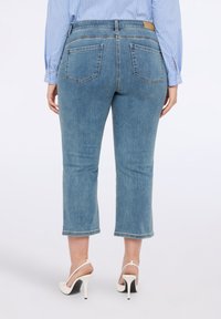 Vaaleansiniset denim-kroppihousut, joissa suora leikkuu, takataskut ja raaka helma. Yhdistetty valkoisiin korkokenkiin.