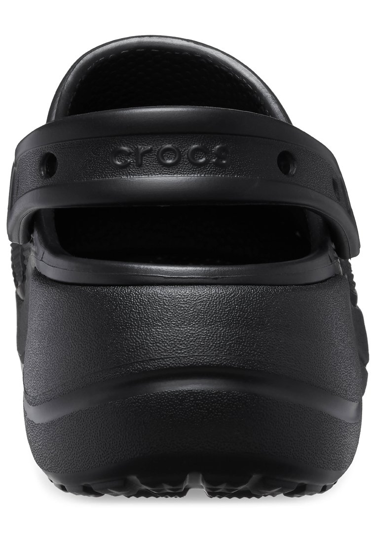 Zuecos Crocs negros con una superficie texturizada, parte trasera abierta y correa de talón ajustable. Presenta el logo de la marca en el talón. Diseño ligero.