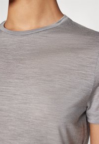 T-shirt cinza de gola redonda com mangas curtas, feita de um tecido leve e suave. Apresenta uma textura subtil e um formato ajustado.