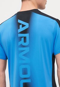 Blå trenings T-skjorte med gradientdesign som fader til svart, med stor tekst "ARMOUR" vertikalt langs ryggen. Glatt, elastisk materiale.