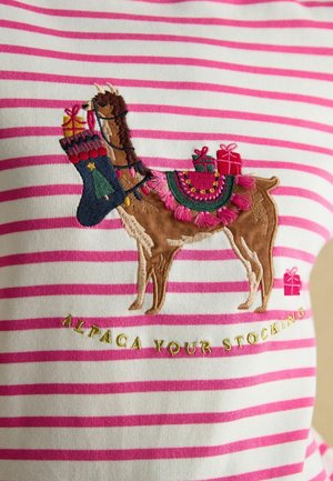 Weißer Stoff mit rosa Streifen, der ein gesticktes braunes Lama zeigt, das einen Strumpf und Geschenke hält, mit dekorativen Akzenten und Text darunter.