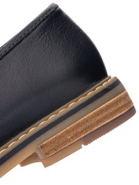 Black leather shoe heel with layered sole featuring beige stitching, black accent, and textured brown rubber outsole.