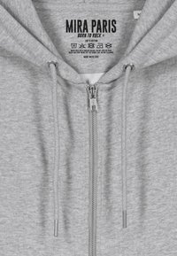 Felpa grigia con zip realizzata in cotone al 100%, dotata di zip metallica con etichetta del marchio, coulisse e etichetta con le istruzioni per la cura all'interno.