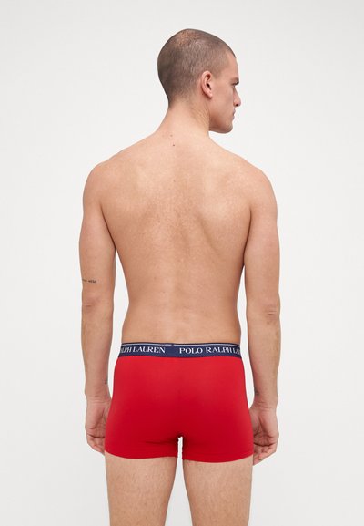 Punaiset puuvillabokserit, joissa on tummansiniset vyötärönauhat, joissa lukee valkoisella "POLO RALPH LAUREN". Sileä pinta, tiukka istuvuus. Yksinkertainen muotoilu.