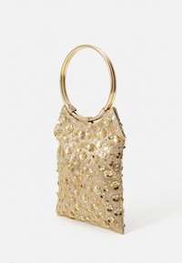 Beige handbag with gold floral embellishments and sequins. Features a circular gold handle. Smooth texture with a structured shape.
