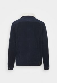 Giacca in velluto a coste blu navy con colletto in pile bianco, maniche lunghe e polsini con bottoni vista da dietro.