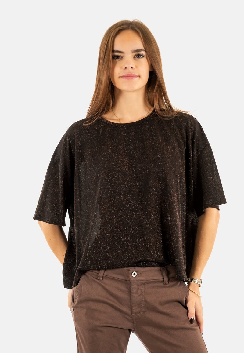 Camisa negra de manga corta con un corte holgado, que presenta sutiles destellos. Textura suave y escote redondeado, combinada con pantalones marrones.