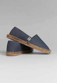 Espadrilles de lona azules con suela de cuerda. Presentan un diseño de perfil bajo y una pequeña etiqueta de logo. Sin patrones o acentos significativos.