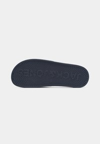 Navy rubber shoe sole with a textured grip pattern, featuring the embossed logo and zigzag tread for traction.
