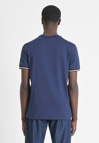 Camiseta de manga corta azul marino con acentos contrastantes en negro y blanco en el cuello y las mangas, fabricada con un suave tejido de mezcla de algodón.