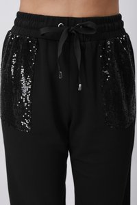 Μαύρο παντελόνι φόρμας με γυαλιστερές μαύρες τσέπες από παγιέτες, ελαστική μέση και κορδόνι με μεταλλικά άκρα. Μαλακή υφή υφάσματος.