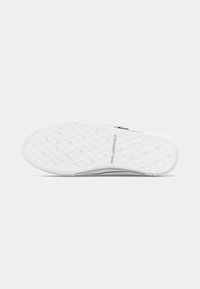 Witte rubberen zool van sneakers met een getextureerd geometrisch patroon en "KARL LAGERFELD" branding verdiept in het midden.