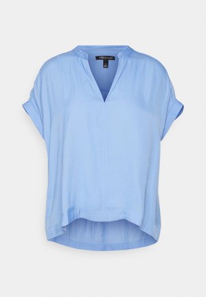 Jasnoniebieska bluzka z krótkim rękawem, z podwiniętymi mankietami, dekoltem w serek oraz lekko dłuższym, zaokrąglonym tyłem.