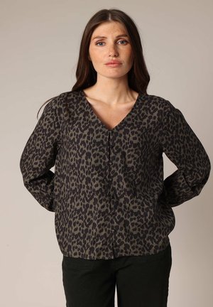 Chemise à manches longues avec un col en V en tissu vert olive foncé, présentant un motif léopard noir et de petits détails de boutons sur le devant.
