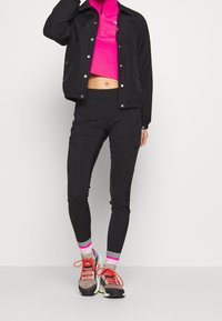 Czarna lekką kurtka z zamkiem z przodu, zestawiona z różowym topem z długim rękawem i krótkim kroju oraz wąskimi czarnymi spodniami z kieszeniami. Wielokolorowe sneakersy.
