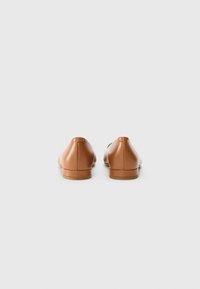 Ballerines en cuir marron avec une texture lisse, un petit talon rectangulaire et un design minimaliste, vues de l'arrière.