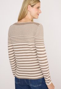 Pull rayé beige et crème, avec des manches longues, une texture côtelée et un décolleté bateau. Assorti avec un jean bleu, montrant le dos.
