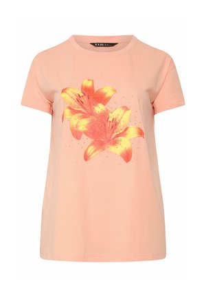 Chemise rose clair à manches courtes avec deux grandes lis orange et jaune imprimées sur le devant, agrémentée de petits points scintillants.