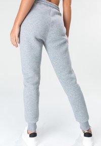 Grijze katoenen sweatpants met een elastische tailleband en taps toelopende benen, met een zachte textuur en geribde manchetten. Schoenen met een contrasterende hakdetail.