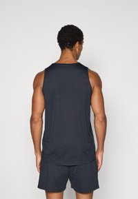 Marineblaues Athletik-Tanktop mit rundem Ausschnitt, ärmellosem Design und strukturiertem Stoff. Wird mit passenden Shorts für einen abgestimmten Look getragen.