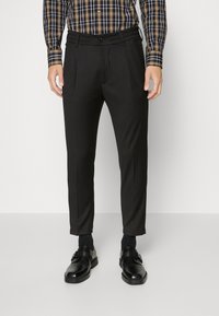 Zwarte op maat gemaakte broek met plooien, met een gladde textuur en een aansluitend ontwerp. Draag deze met zwarte nette schoenen en accentueer met een geruite blouse.